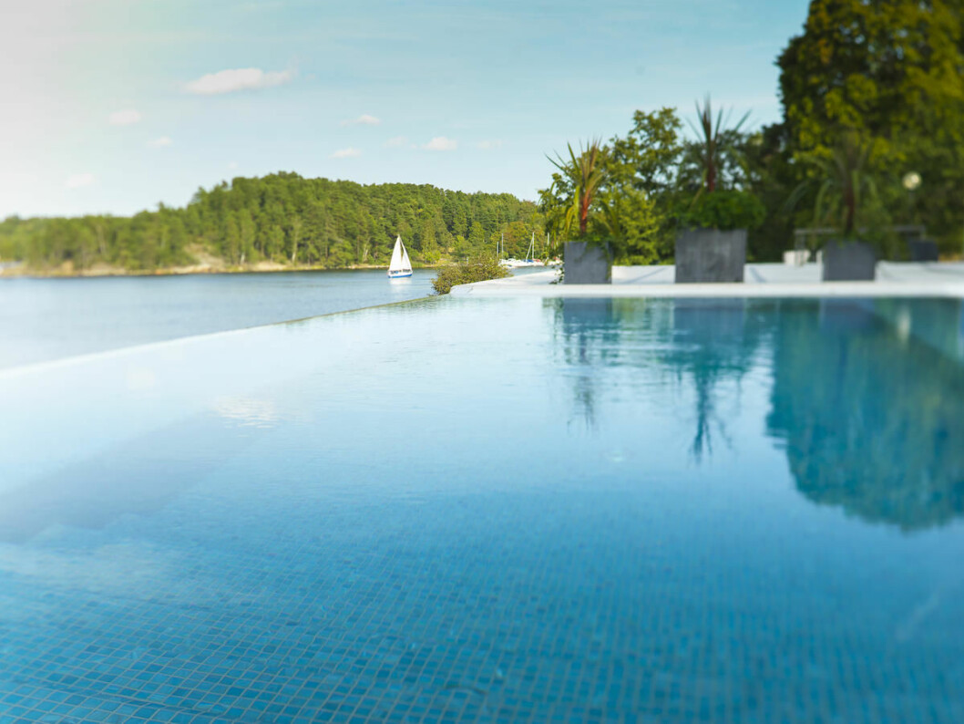 Bada med utsikt över Östersjön på Skepparholmen. Klicka på bilden för att komma direkt till hotellet. Kanten av en pool med utsikt över havet och massa skog