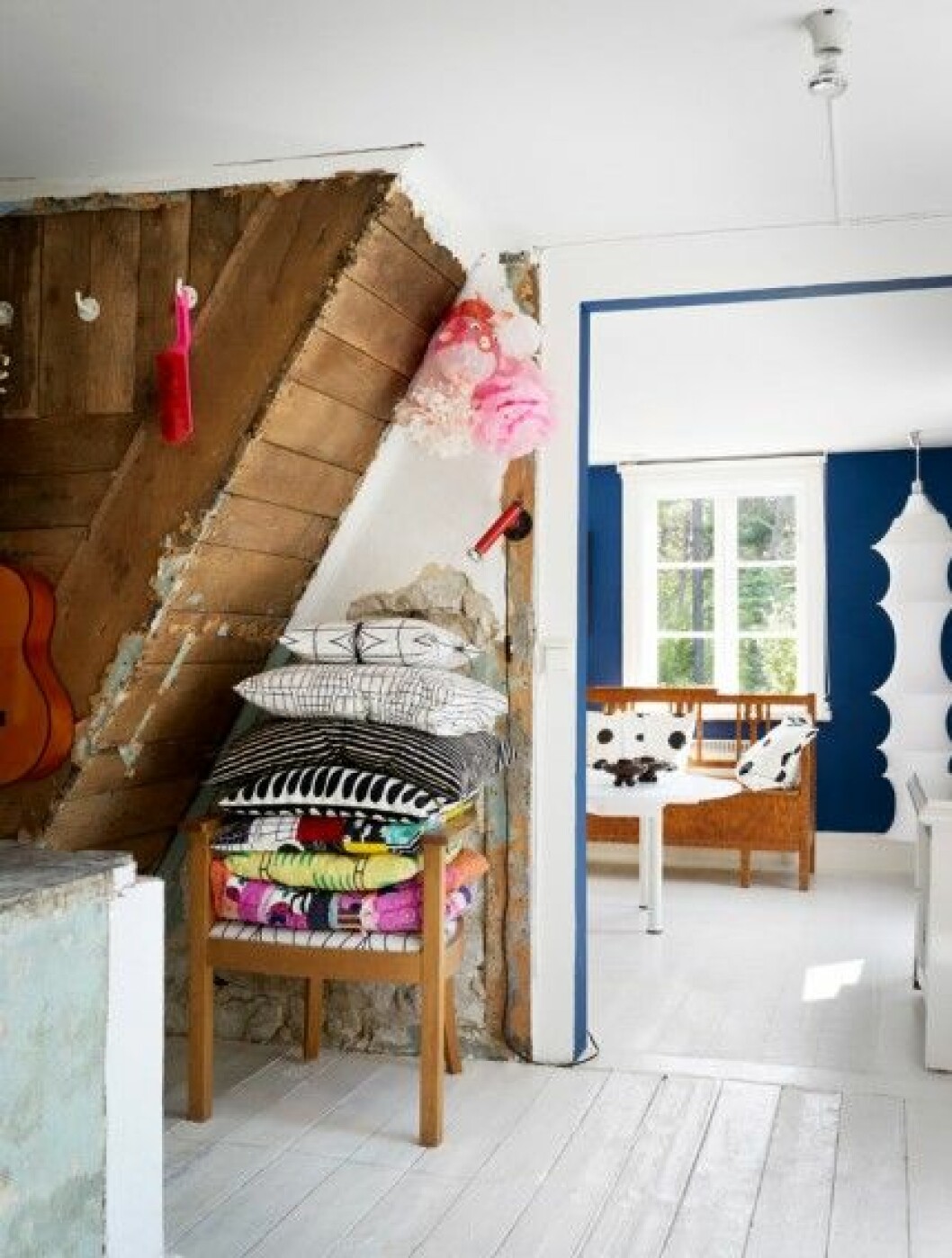 I hallen har trappa och väggar lämnats råa – kanske kommer de en dag att ge plats för mer förvaring. Kuddarna är omklädda i stuvar från bland annat Ikea. Den lilla parstugan har fått en vit grund med ljusa golv. I bakgrunden skymtar den blå salen. Gotländsk kökssoffa och kuddar i tyg från Ikeas <em>PS</em>-kollektion. Ljusstakarna är egentligen gamla isolatorer som grannen hittade i vedboden. Lampa <em>Falkland</em>, design Bruno Monari, Danese Milano. I hallen har trappa och väggar lämnats råa – kanske kommer de en dag att ge plats för mer förvaring. Kuddarna är omklädda i stuvar från bland annat Ikea. Den lilla parstugan har fått en vit grund med ljusa golv. I bakgrunden skymtar den blå salen. Gotländsk kökssoffa och kuddar i tyg från Ikeas PS-kollektion. Ljusstakarna är egentligen gamla isolatorer som grannen hittade i vedboden. Lampa Falkland, design Bruno Monari, Danese Milano.