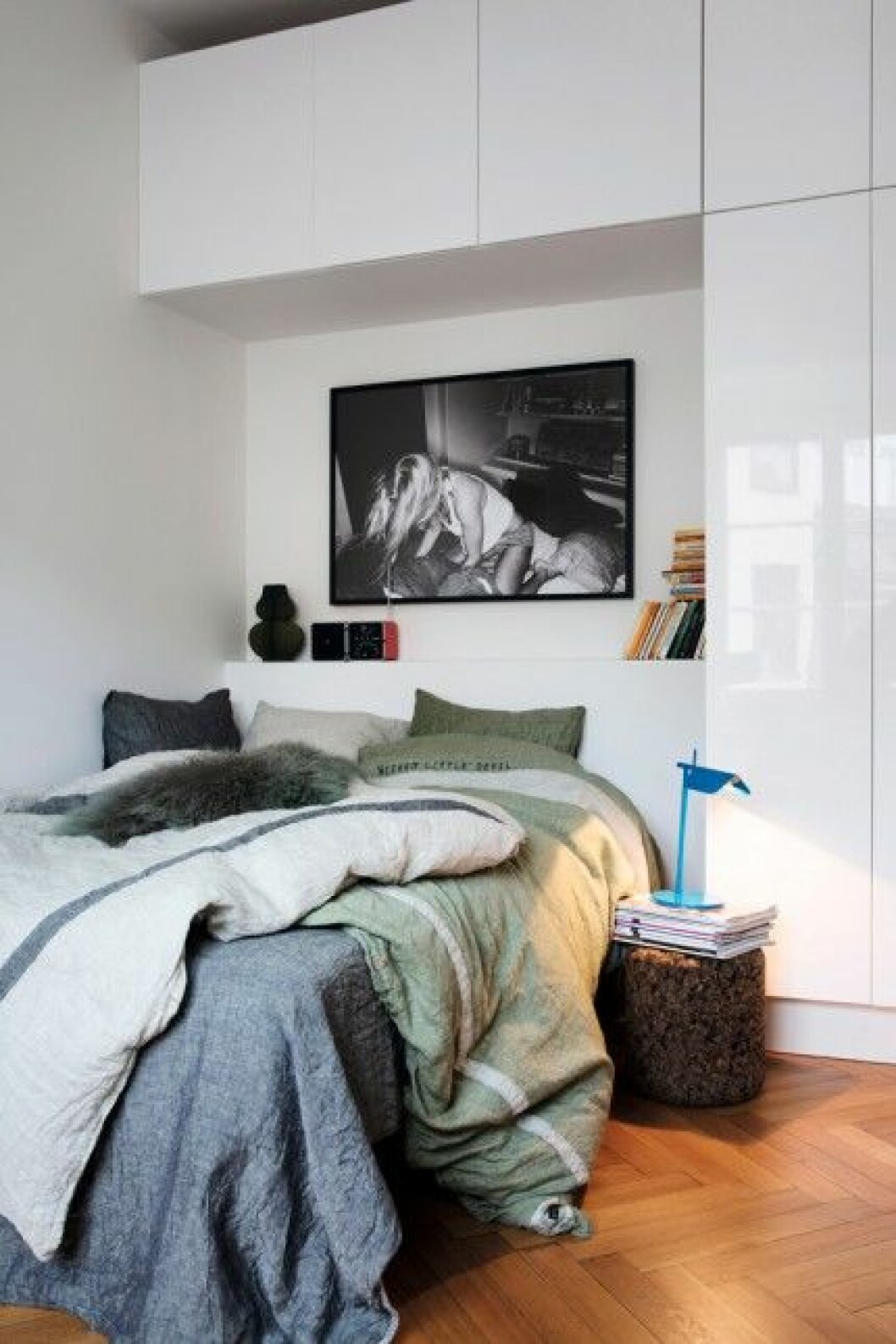 En trappa ner ligger gästrummet. Sängkläder från Dirty Linen. Fotot ovanför sängen är en kampanjbild från samma företag. Nattduksbord Cork Stool av Jasper Morrison för Moooi. Bordslampa som sänglampa Tab, design Edward Barber och Jay Osgerby för Flos. Sovrum-inbygd-garderob-lovely-linnen-fotokonst-bokförvaring-sängbord-sänglampa-111