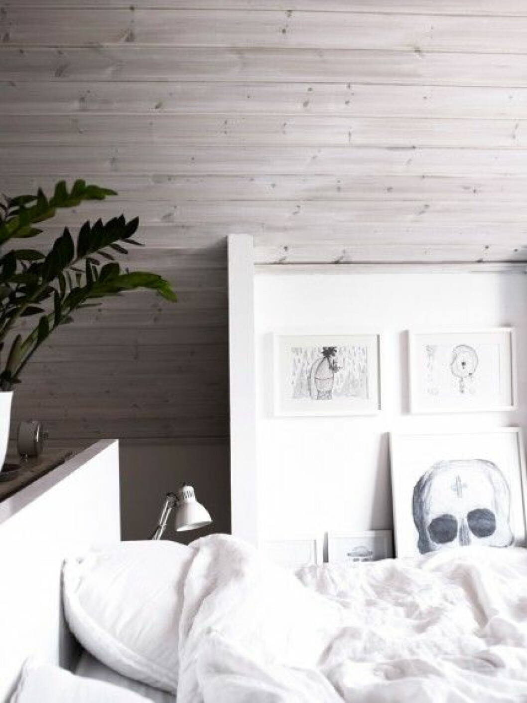 Bredvid sängen står en samling inramade blyertsteckning av sonen Robert. sovrum-svart-vitt-grått-tavelvagg-inspiration-foto-anna-kern