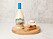 en semla, ett glas med likör och en flaska som står på en rund skärbräda i trä