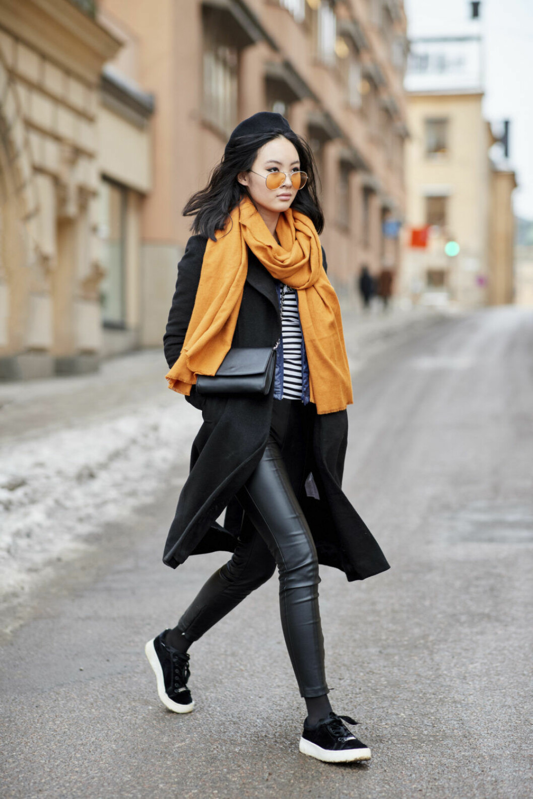 Kvinna i svart outfit med orangea detaljer.