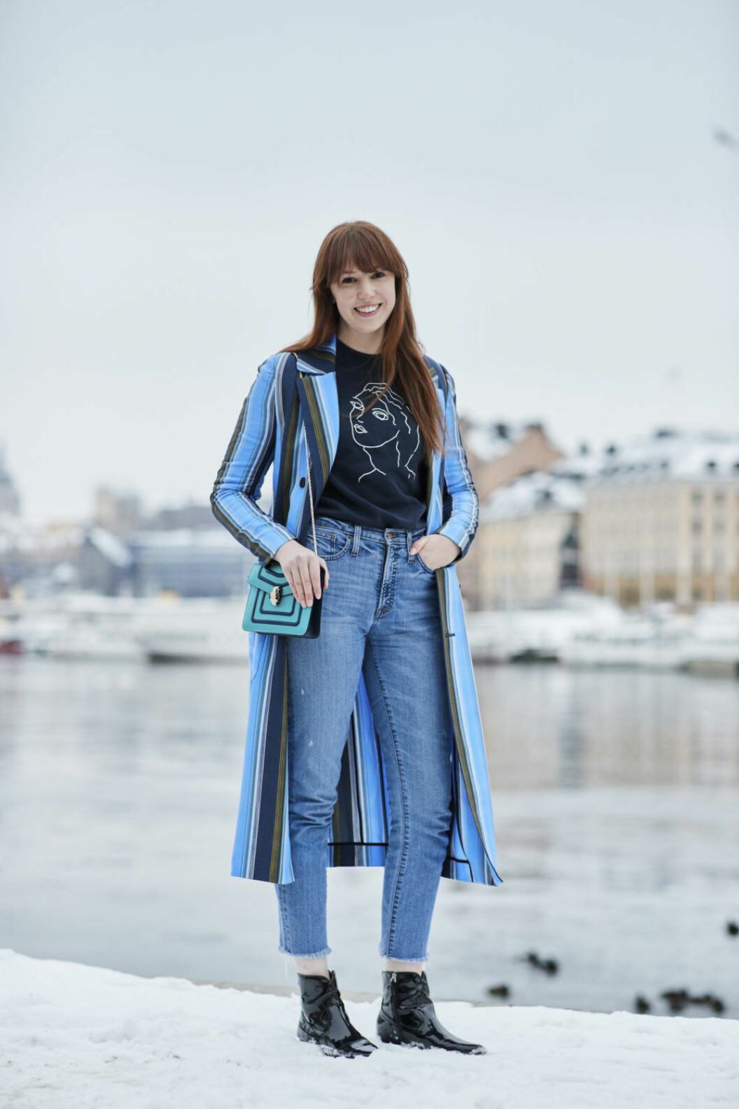 Kvinna i jeans och blårandig kappa