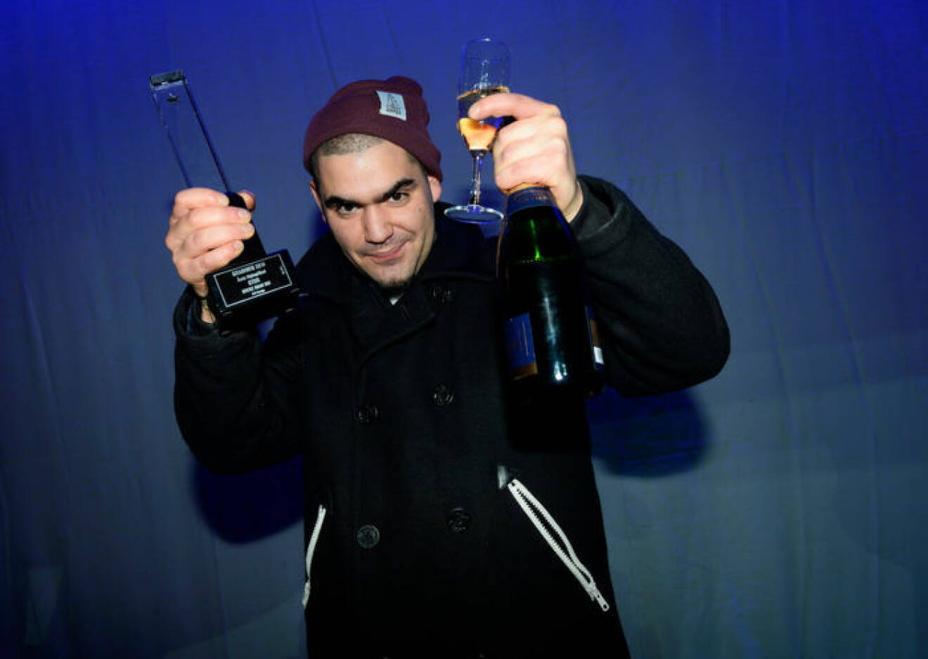 Rapparen Stor med en grammis och ett glas champagne i sin hand.