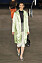 Modell i grön sidenkappa, topp i meshtyg, byxor i trekvarts, silvriga skor och en svart väska, Tory Burch SS23