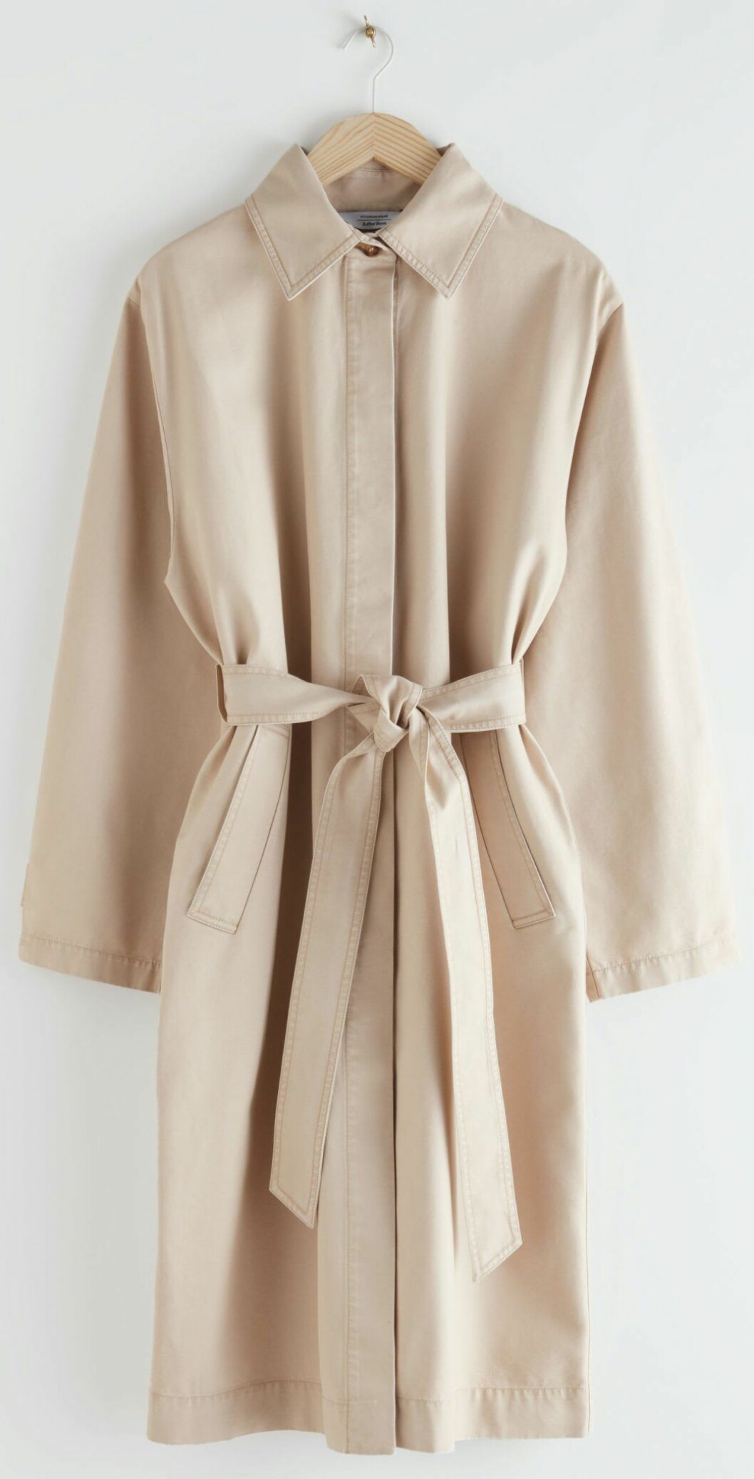 Ljusbeige trenhcoat i rak modell och midjebälte från & other stories.