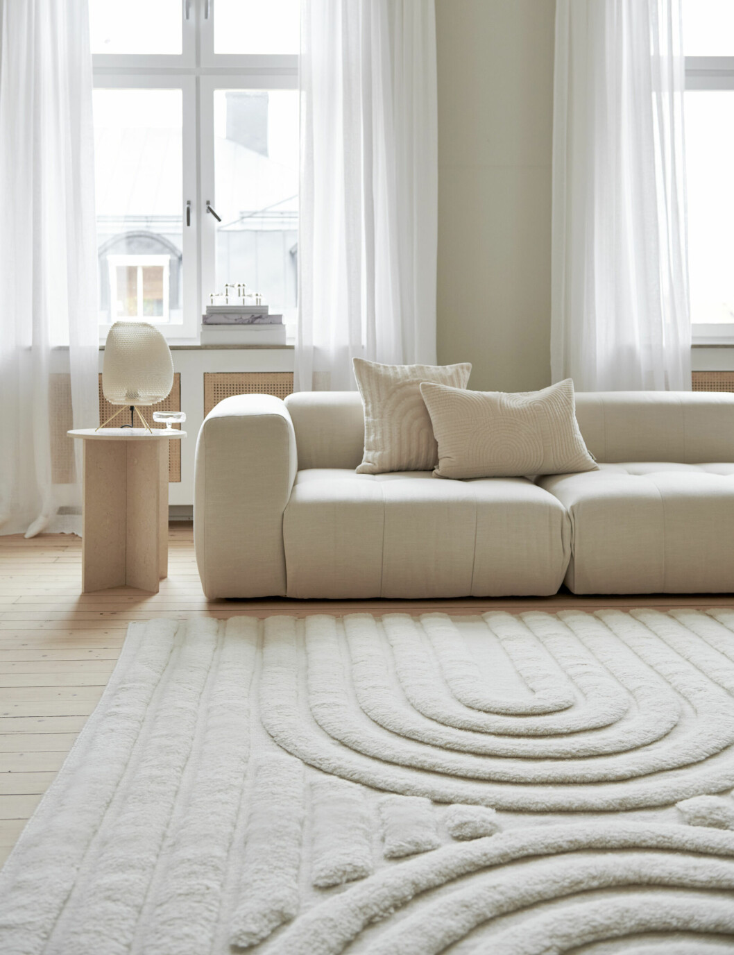 vardagsrum med beige inredning och organisk matta med valv