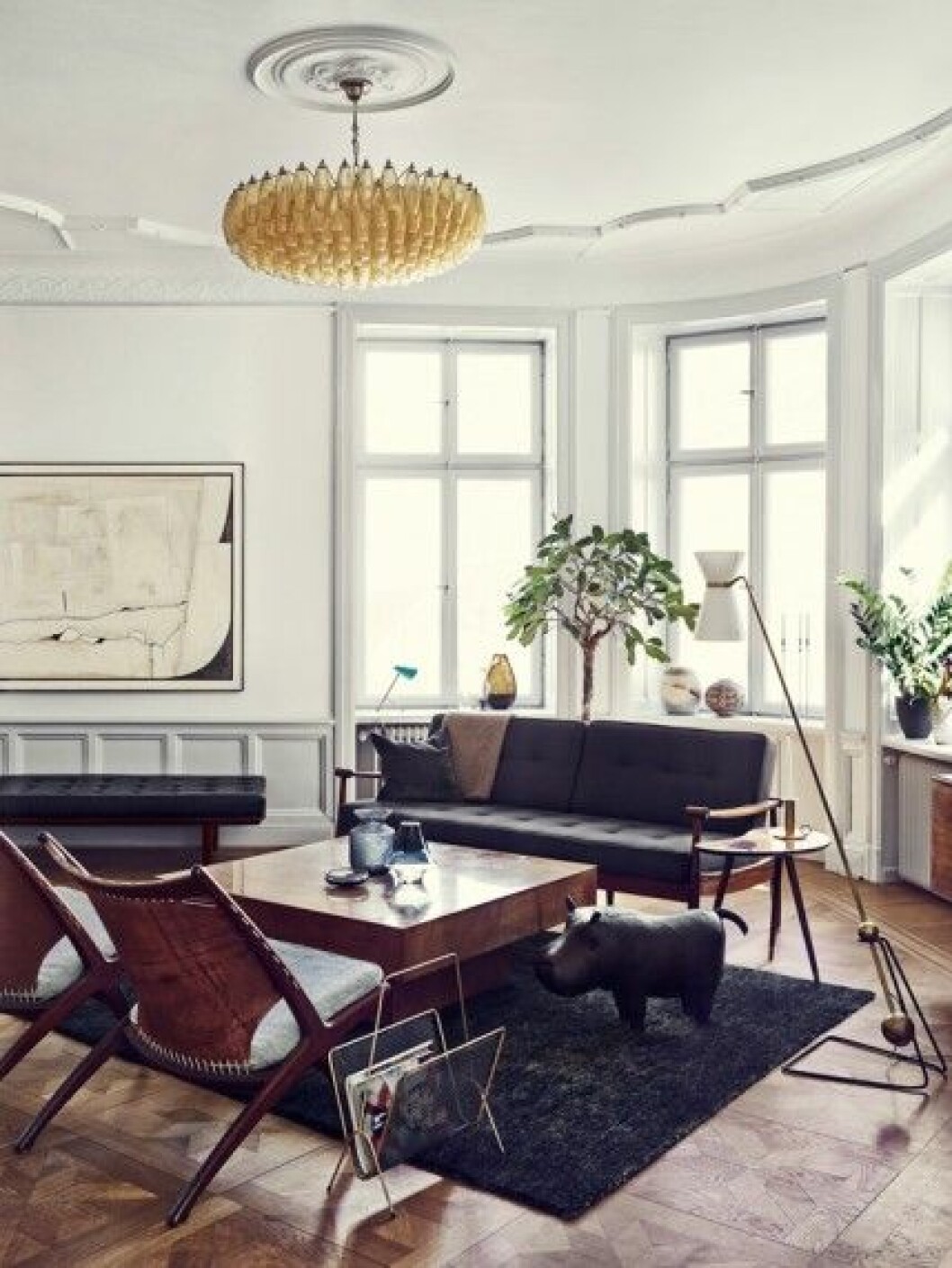 Hörnfönstret och stjärnparketten var två av sakerna som fick Joanna på fall. Flodhäst i brunt skinn, design Dimitri Omersa & Co för Svenskt Tenn. Den danska soffan har Davids mamma klätt om. Soffbord Aldo Tura och sidobord av bröderna Johanson i Markaryd. Golvlampan är signerad den franska designern Pierre Guariche och taklampan italienaren Carlo Scarpa för Venini. Fåtöljer Krysset av norska formikonen Fredrik Kayser. vardagsrum-midcentury-italian-italiensk-inspiration