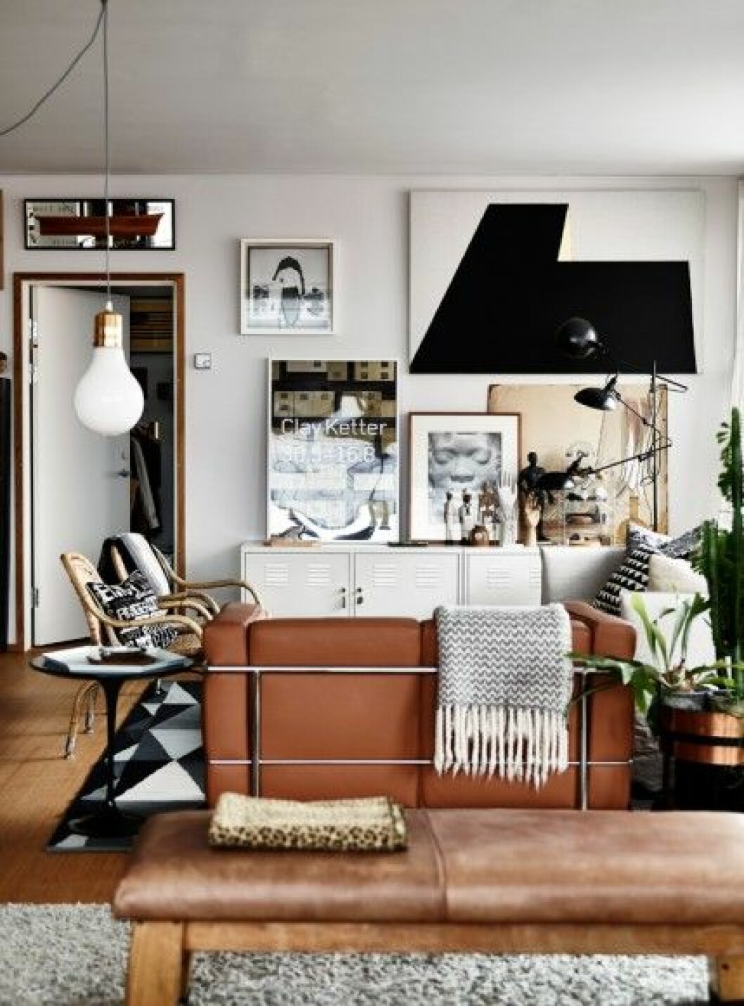 Det öppna rummet löper längs den stora altanen och i bortre änden ligger Gerthel.vardagsrumsdelen. Vit soffa Ghost av Paola Navone, Gervasoni. Den mindre i ljust läder är Petit Comfort av Le Corbusier. Den stora grafiska målningen är av Arne Ohlsson, affisch av Clay Ketter och fotografiet ovanför är av Joseph Beuys. Vita plåtskåp från Ikea. Den trearmade lampan är köpt på Olsson & Gerthel. vardagsrum-tavelvägg-brun-skinnsoffa-inspiration-foto-andrea-papini