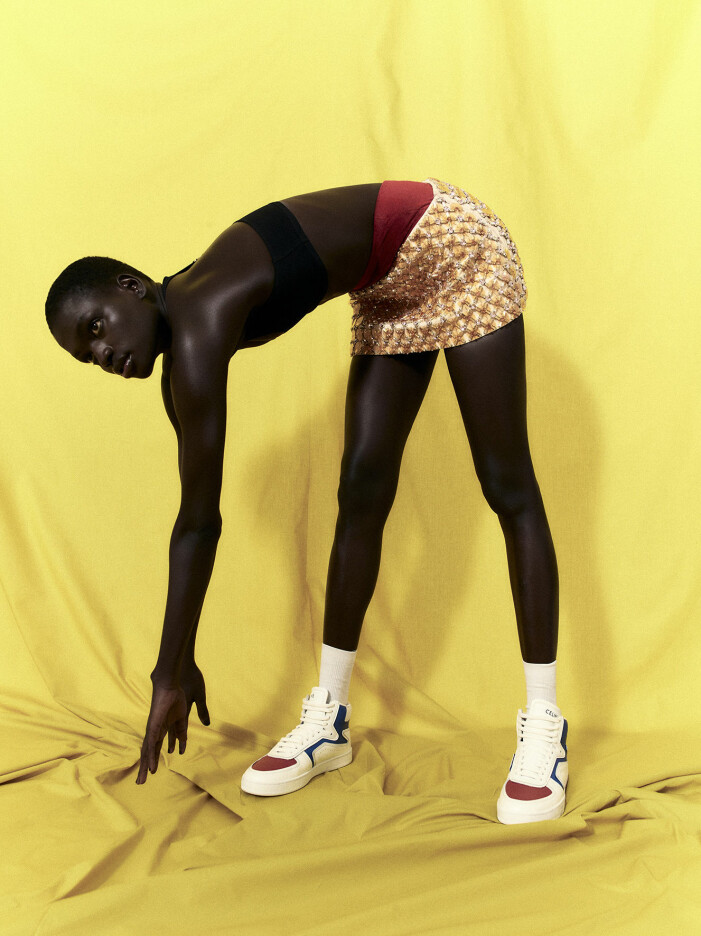 Bikinitopp, 3 100 kr, och sneakers, 7 500 kr, båda Celine by Hedi Slimane. Shorts och kjol, pris vid förfrågan, båda Miu Miu. Strumpor, 49 kr, Arket. Modellen har på sig en svart bikinitopp, röda shorts och en guldig kjol
