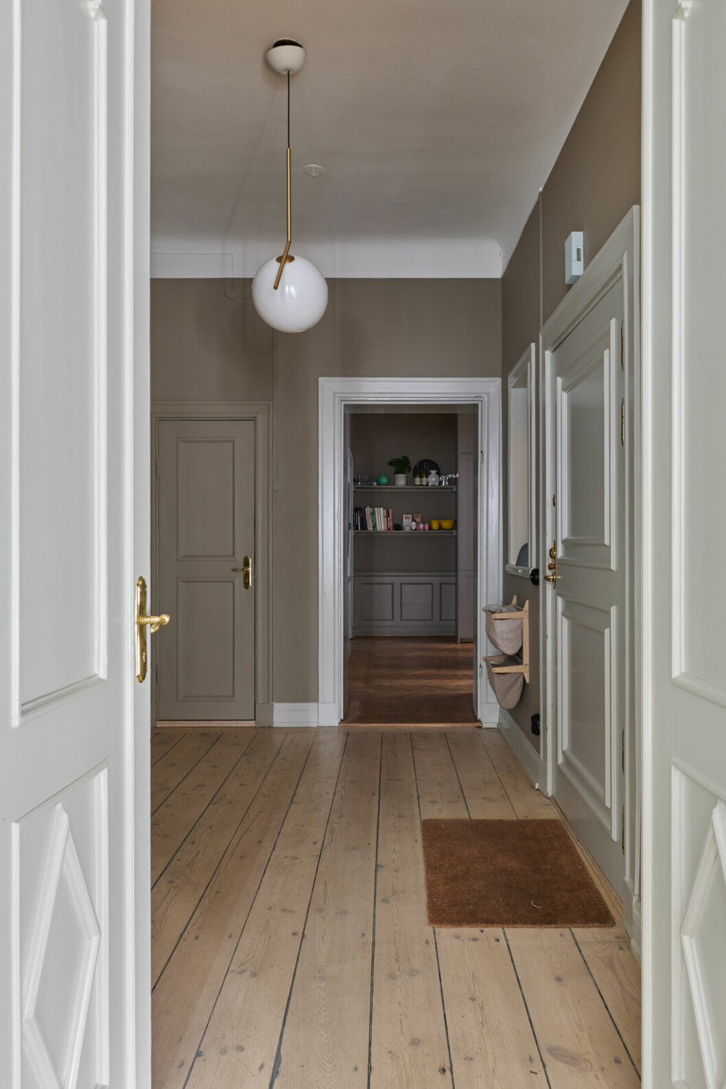 Hallen leder vidare till både kök och vardagsrum. hall med sekelskiftesdetaljer