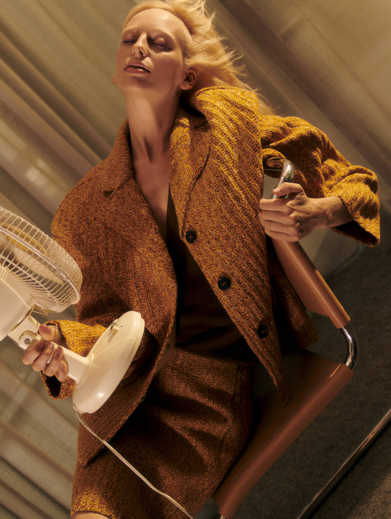 Modellen har på sig en stickad jacka med matchande kjol i gult, med en brun tröja under, allt från Miu Miu.