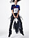 Fotomodellen har på sig en pikétröja från Polo Ralph Lauren X Fortnite, svarta byxor med fransar och en väska, även den med fransar från Versace